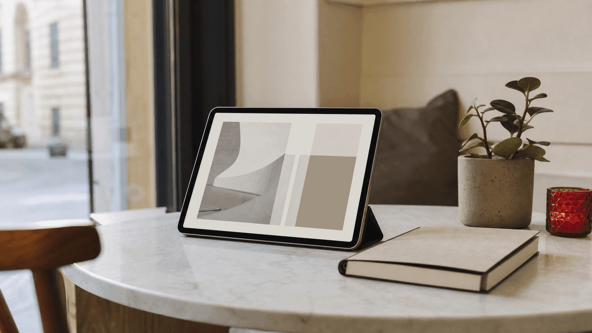 A calm minimalist single-page business website shown on a tablet propped on a clean cafe-style table next to a plant and a notebook, no people, quiet uncluttered feel, soft natural light, photorealistic, no text