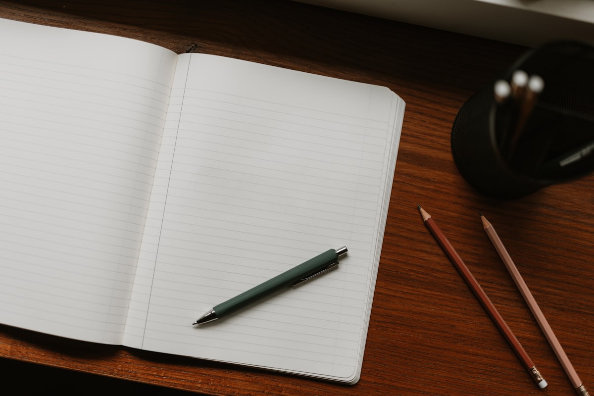 Aufgeschlagenes Notizbuch mit Stift auf einem Holztisch