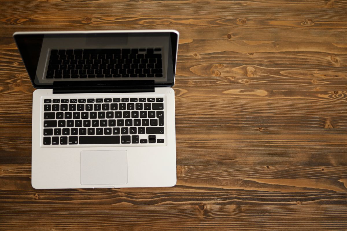 Aufgeklappter Laptop auf einem Holztisch von oben